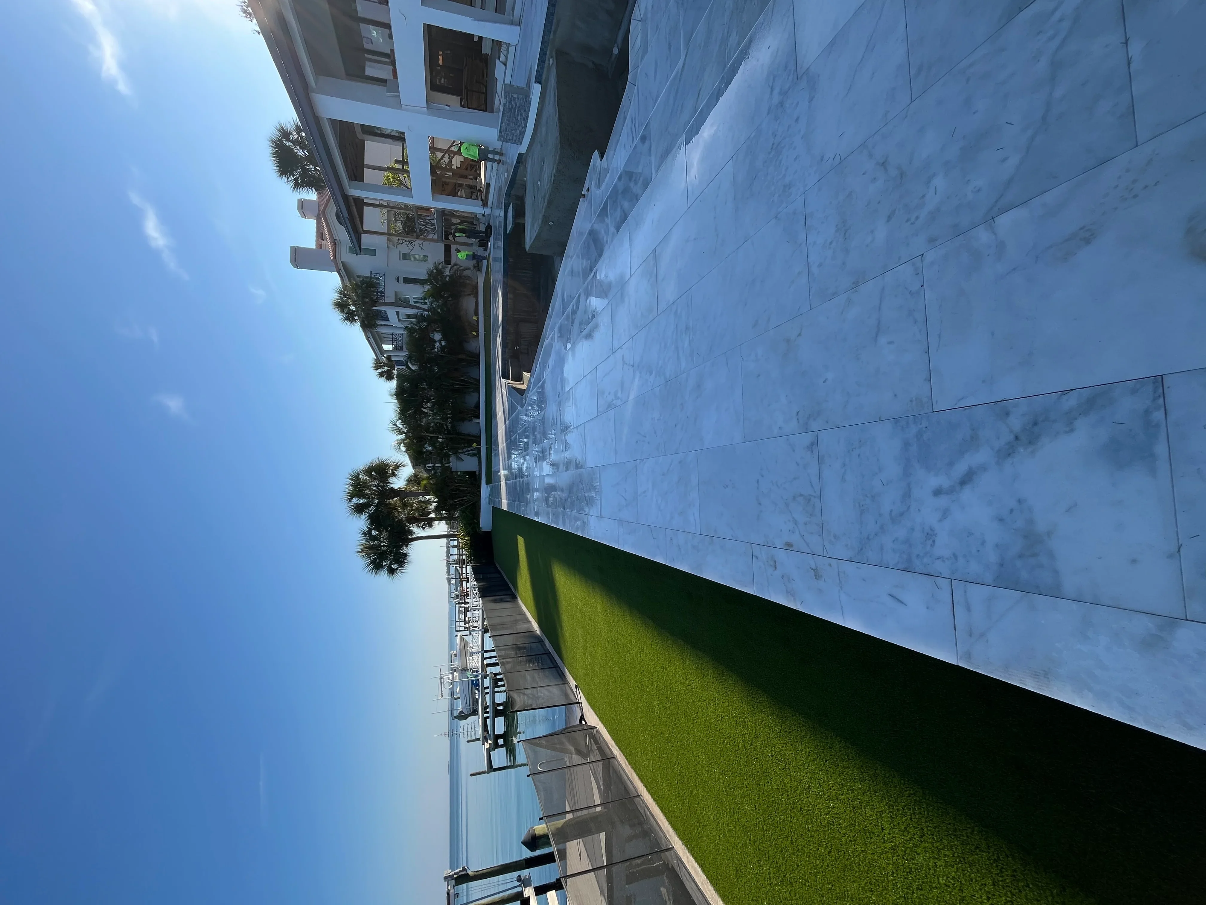 Synthetic turf lawn installation with palm trees and modern white residential home
