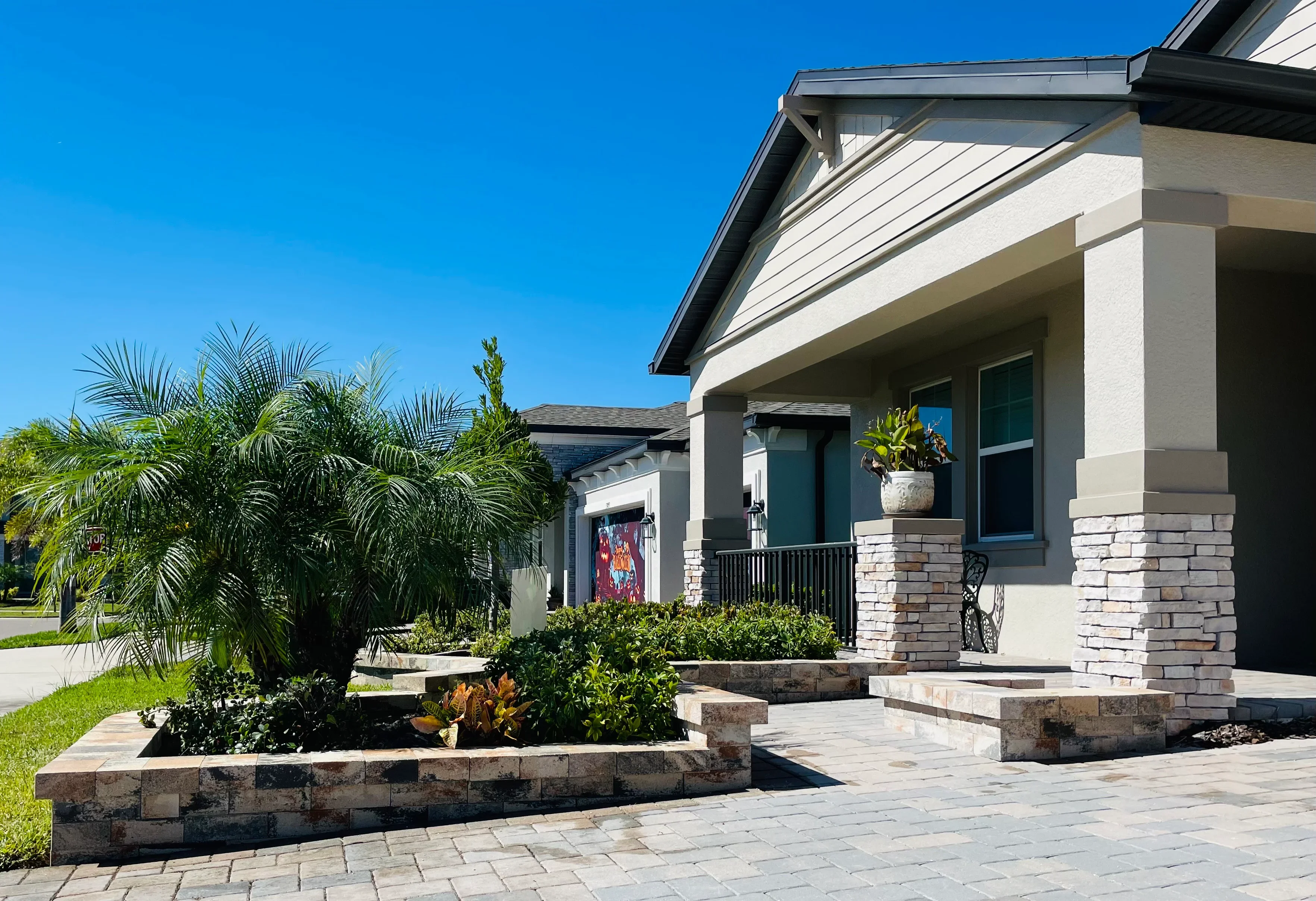 Raised stone planting beds with tropical plants and shrubs in front of modern home