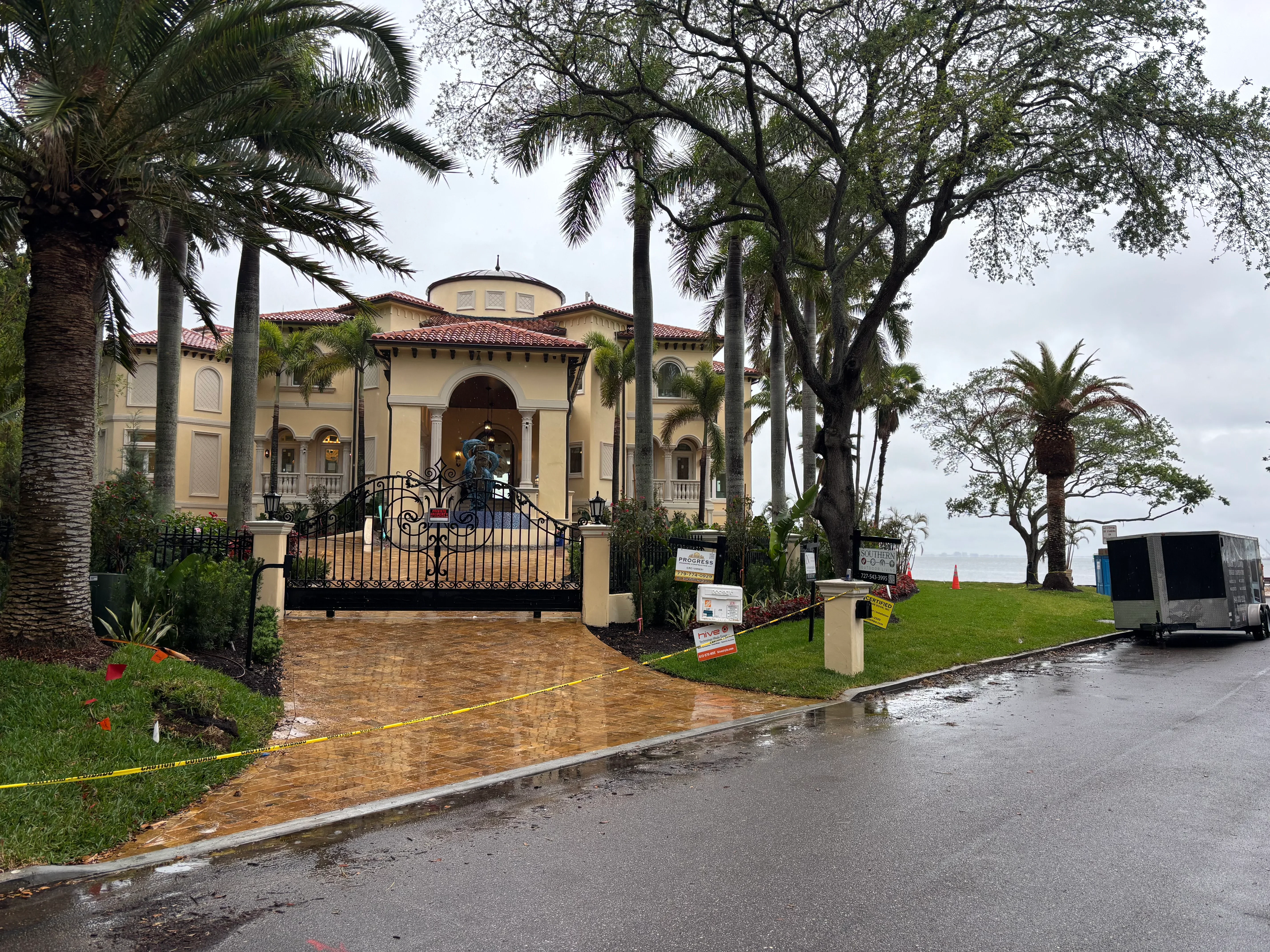Manicured lawn, palm trees, and planting beds framing Mediterranean estate entrance