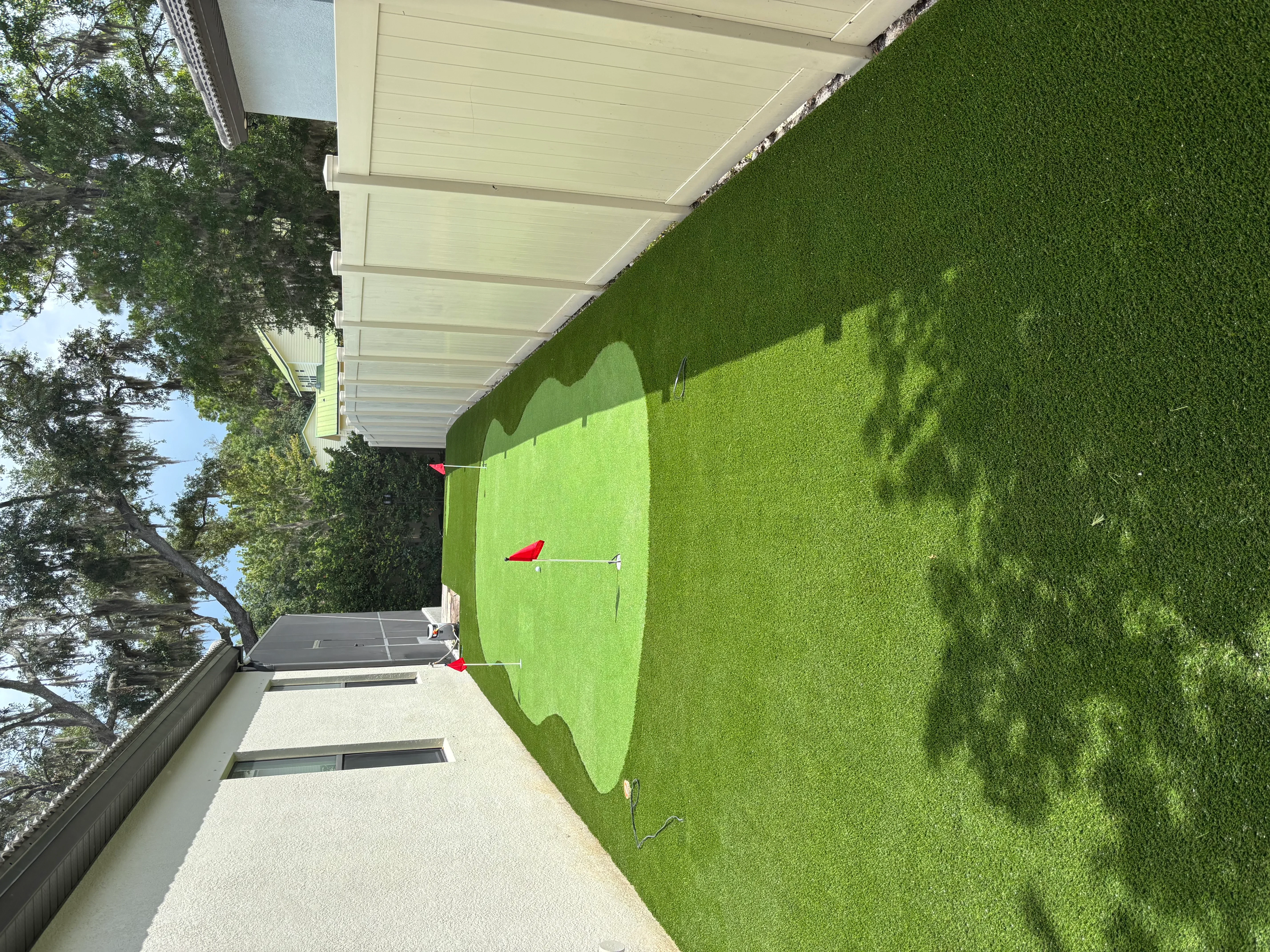 Synthetic turf lawn with shade pergola structure and golf putting green markers