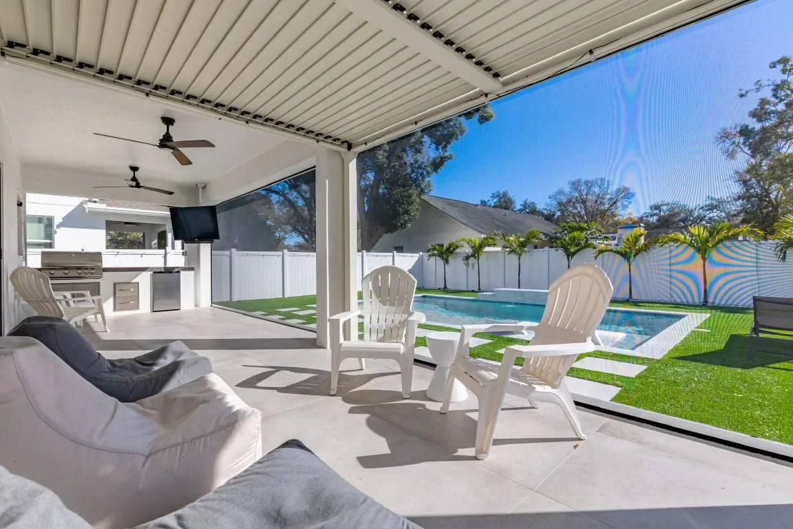 Synthetic turf, palm trees, and pool deck landscaping with white privacy fence