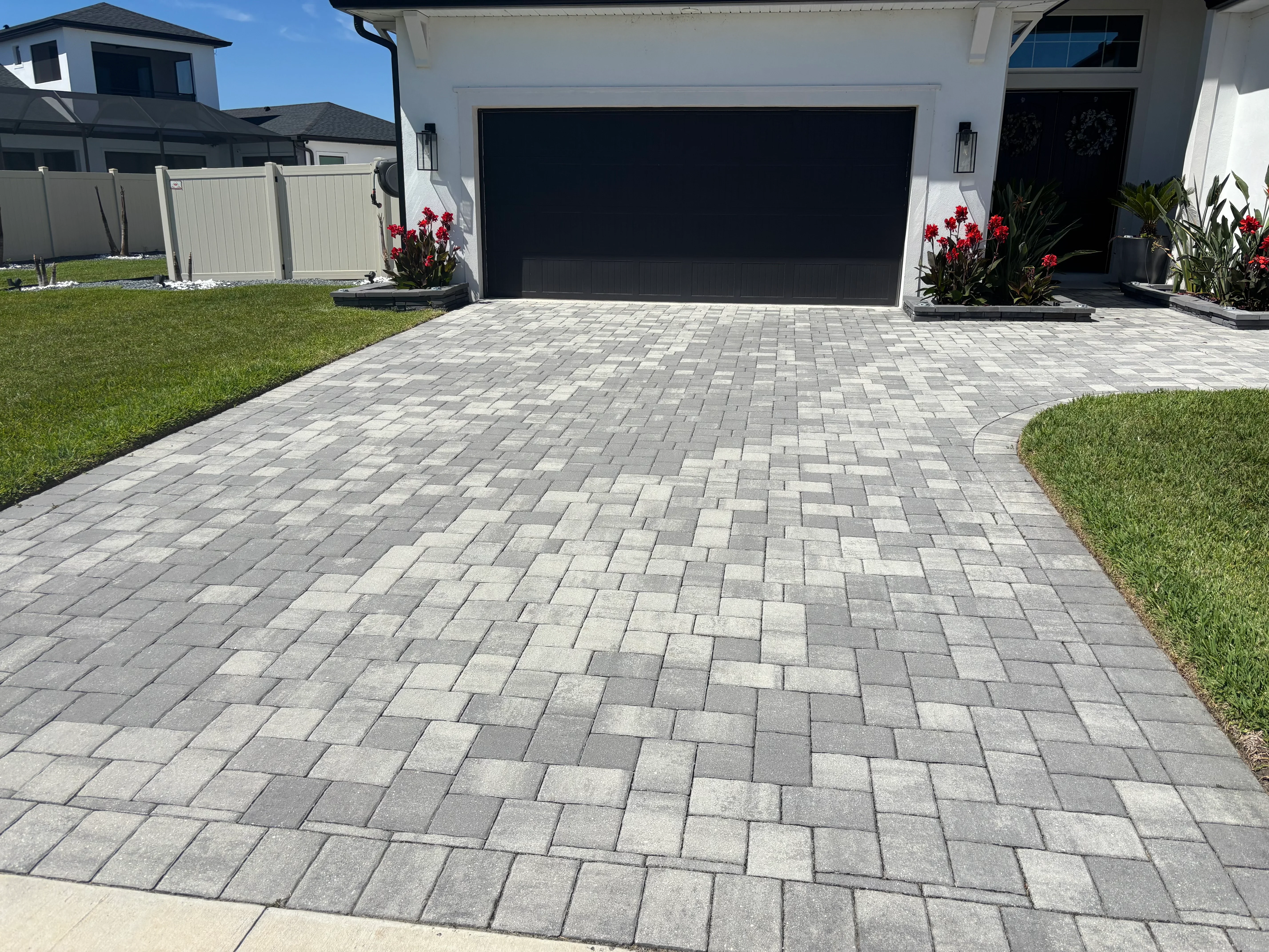Gray and charcoal permeable pavers in herringbone pattern with landscape planting beds and lawn edging